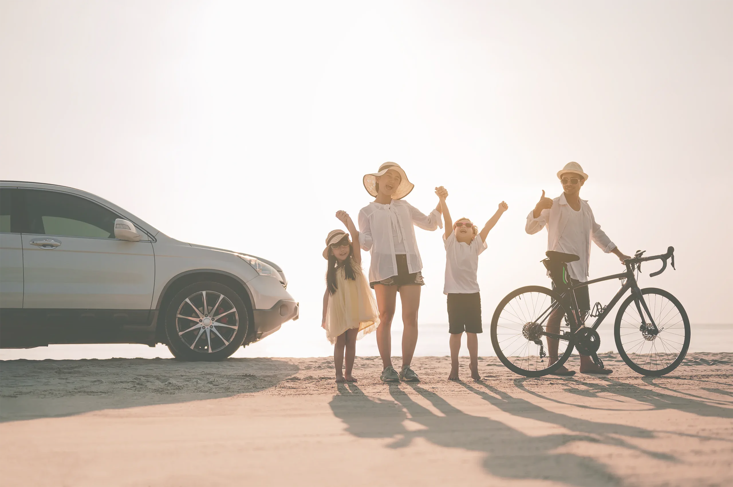 A family on a beach road trip next to their car
